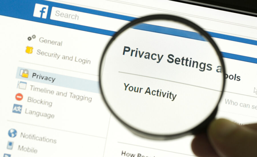 Magnifying glass highlighting the 'Privacy Settings' section on a social media platform interface, depicting the importance of online privacy management.