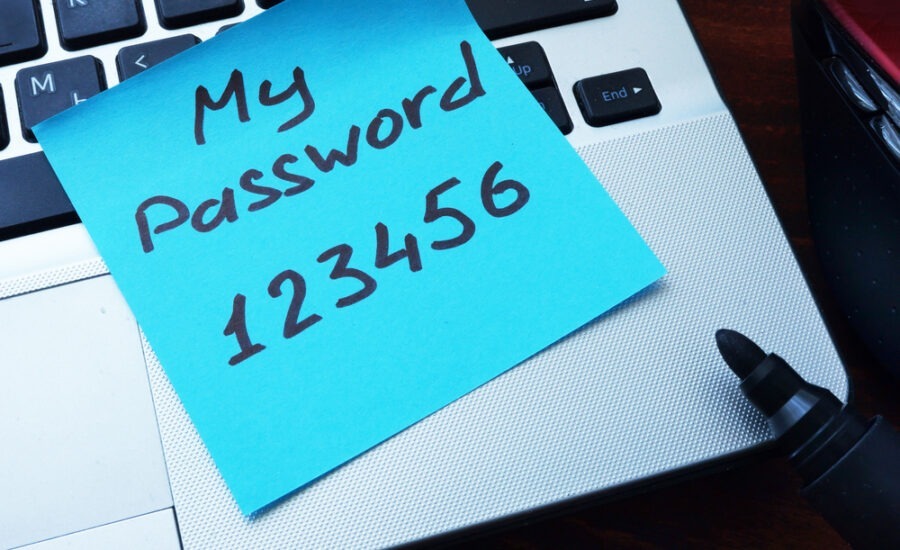 Sticky note with 'My Password 123456' written on it, placed on a laptop keyboard, illustrating poor cybersecurity practices and the risks of weak passwords.