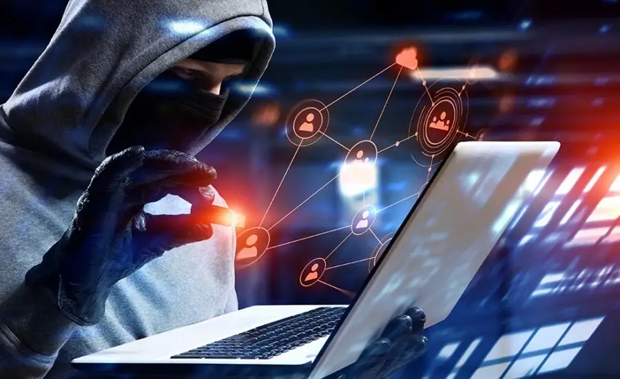 Hooded hacker using a laptop with floating network and social media icons, portraying cybercrime, digital privacy invasion, and unauthorized data access.