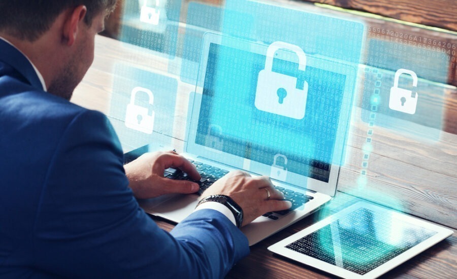 Professional in blue suit working on a laptop with virtual overlay of padlock icons and binary code, signifying data protection and cybersecurity measures in business.