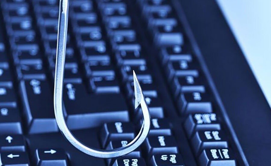 Close-up of a phishing hook symbol resting on a black computer keyboard, representing internet security threats and email scam awareness.